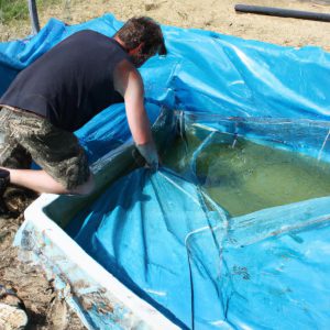 Person installing pond liner material