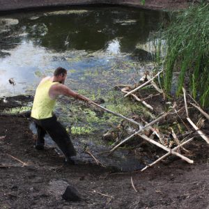 Person clearing pond construction debris